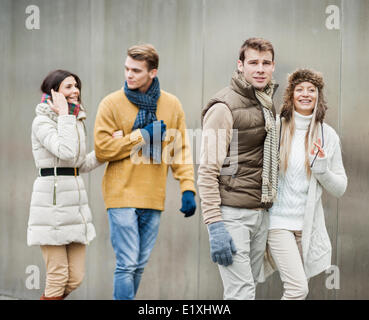 Smiling young couples walking against wall Stock Photo