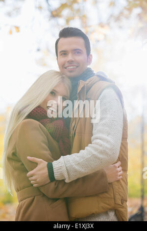 Happy couple in jackets hugging in park Stock Photo