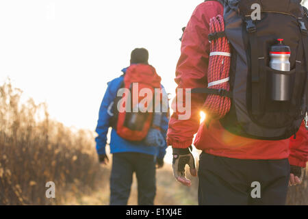 Rear view of male backpackers walking in field Stock Photo