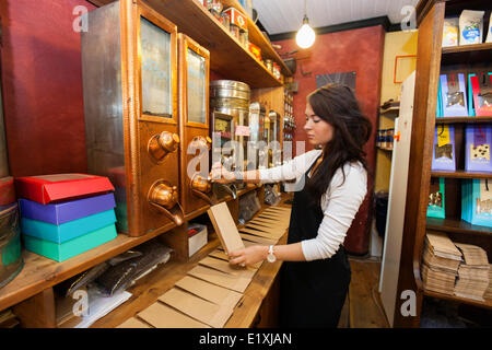 Side view of salesperson dispensing coffee beans into paper bag at store Stock Photo