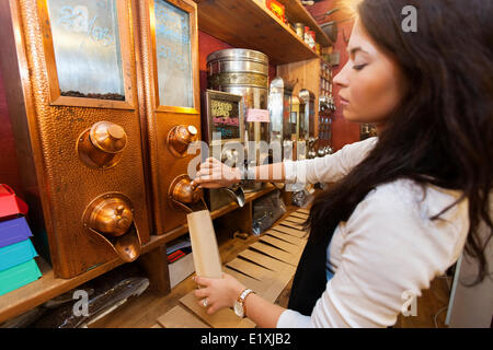 Side view of salesperson dispensing coffee beans into paper bag at store Stock Photo