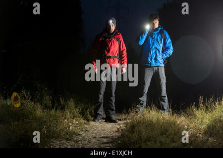 Full length portrait of male hikers with flashlights in field at night Stock Photo