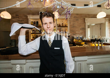 Portrait of confident waiter carrying serving tray in restaurant Stock Photo
