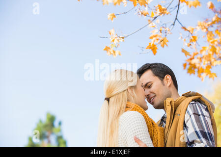 Low angle view of couple kissing against clear sky during autumn Stock Photo