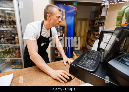 Portrait of salesman using computer at cash counter in supermarket Stock Photo