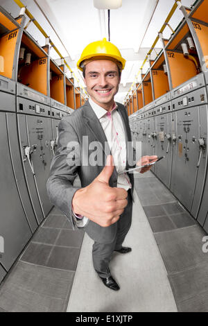 Portrait of smiling supervisor with tablet PC gesturing thumbs up in control room Stock Photo