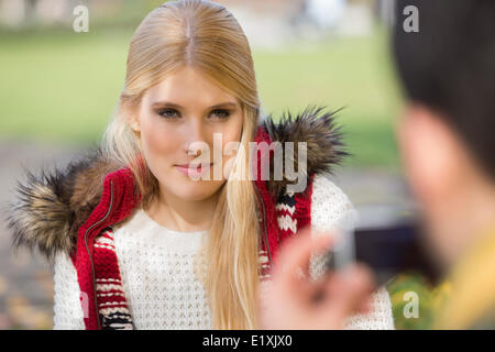 Beautiful young woman being photographed by man in park Stock Photo