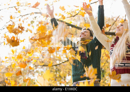 Young couple enjoying falling autumn leaves in park Stock Photo
