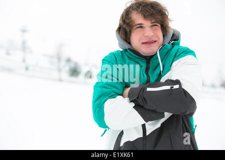 Young man in jacket shivering in snow Stock Photo