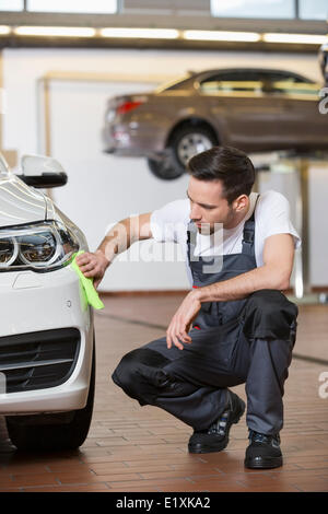 Full length of automobile mechanic cleaning car in workshop Stock Photo