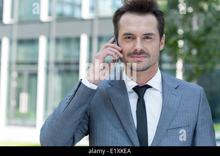 Portrait of confident businessman using cell phone outside office Stock Photo