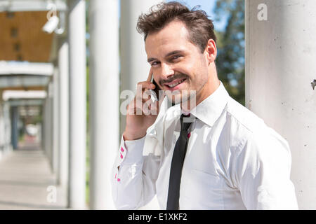 Portrait of smiling young businessman using cell phone outside office Stock Photo