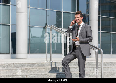 Smiling businessman using cell phone while standing on steps outside office Stock Photo