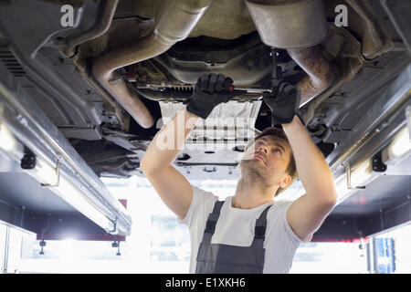 Mid adult automobile mechanic repairing car in workshop Stock Photo