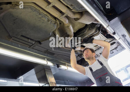 Low angle view of male automobile mechanic repairing car in repair shop Stock Photo