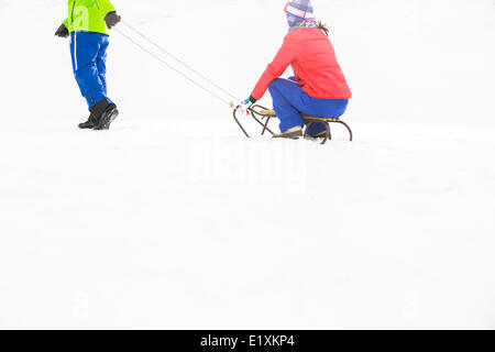 Low section of young man pulling woman on sled Stock Photo