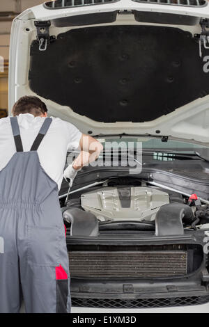 Rear view of male engineer repairing car in automobile repair shop Stock Photo