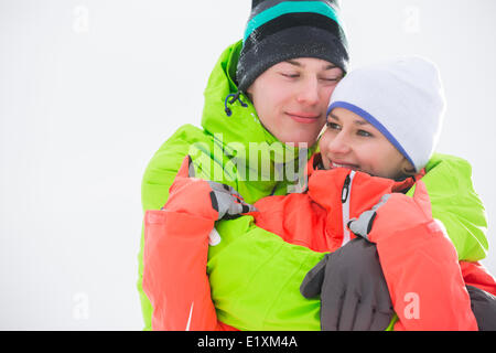 Loving young couple in warm clothing embracing outdoors Stock Photo