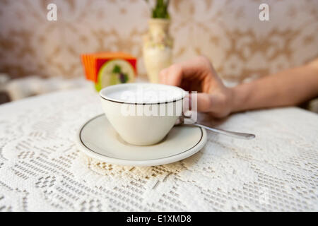 Cropped image of man having cup of coffee at table in cafe