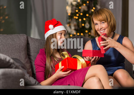 Portrait of happy woman giving Christmas present to daughter at home