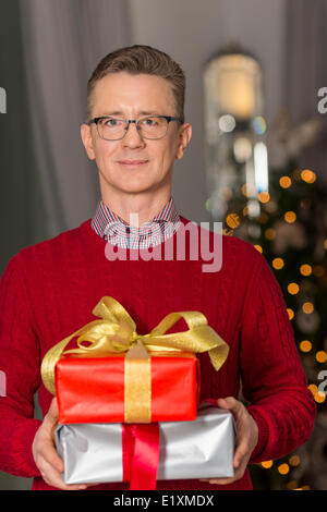 Portrait of mature man holding stack of Christmas presents Stock Photo