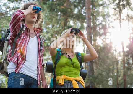 Hiking couple using binoculars in forest Stock Photo