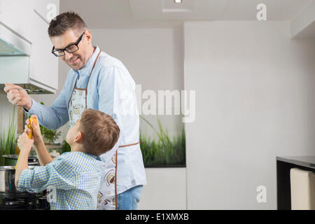 Happy father and son preparing spaghetti in kitchen Stock Photo