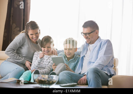 Cheerful family using tablet PC together in living room Stock Photo