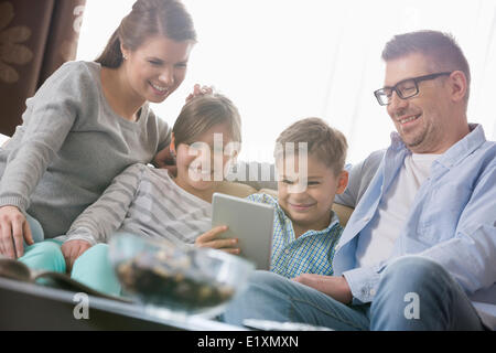 Happy family using digital tablet together in living room Stock Photo