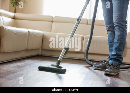 Low section of man cleaning hardwood floor with vacuum cleaner Stock Photo