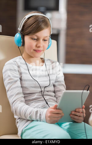 Cute girl listening music while using digital tablet at home Stock Photo