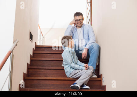 Happy father and son sitting on steps at home Stock Photo