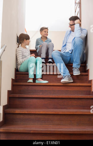 Father sitting with children on steps at home Stock Photo
