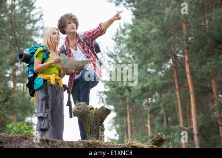 Young hiking couple with map discussing over direction in forest Stock Photo