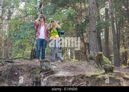Hiking couple using binoculars in forest Stock Photo