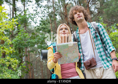 Low angle view of hiking couple with map in forest Stock Photo