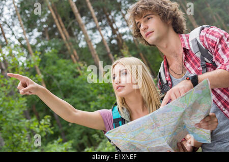 Hiking couple with map discussing over direction in forest Stock Photo