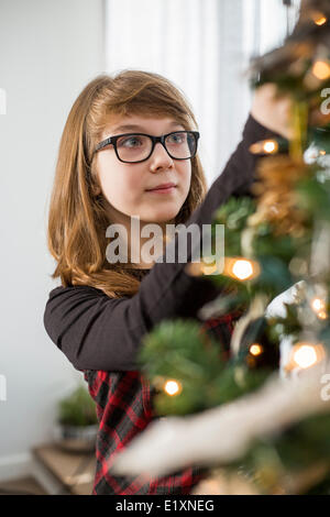 Teenage girl decorating Christmas tree at home