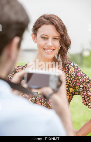 Happy young woman being photographed by man in park Stock Photo