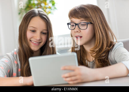 Sisters using digital tablet at table in house Stock Photo