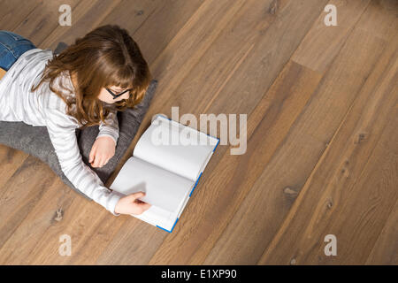 High angle view of teenage girl reading book on floor at home Stock Photo