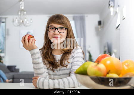 Portrait of teenage girl holding apple at home Stock Photo