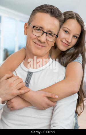 Portrait of affectionate girl embracing father from behind at home Stock Photo