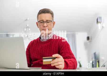Mature man using credit card and laptop to shop online at home Stock Photo