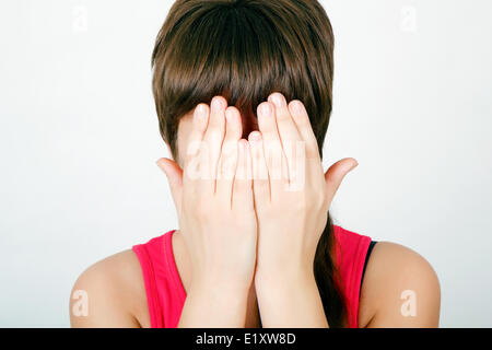 girl covers her face with both hands Stock Photo