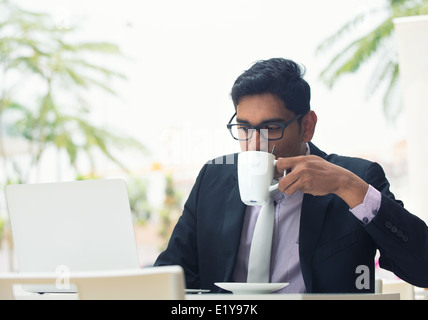 young indian business male on laptop and coffee at a cafe Stock Photo