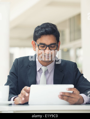 young indian business man with a tablet computer and coffee at a cafe Stock Photo