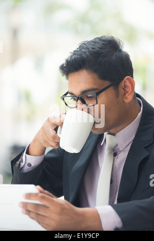 young indian business man with a tablet computer and coffee at a cafe Stock Photo