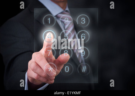 A businessman entering a password onto a glass screen keypad. Stock Photo