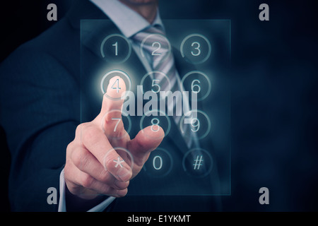 A businessman entering a password onto a glass screen keypad. Stock Photo